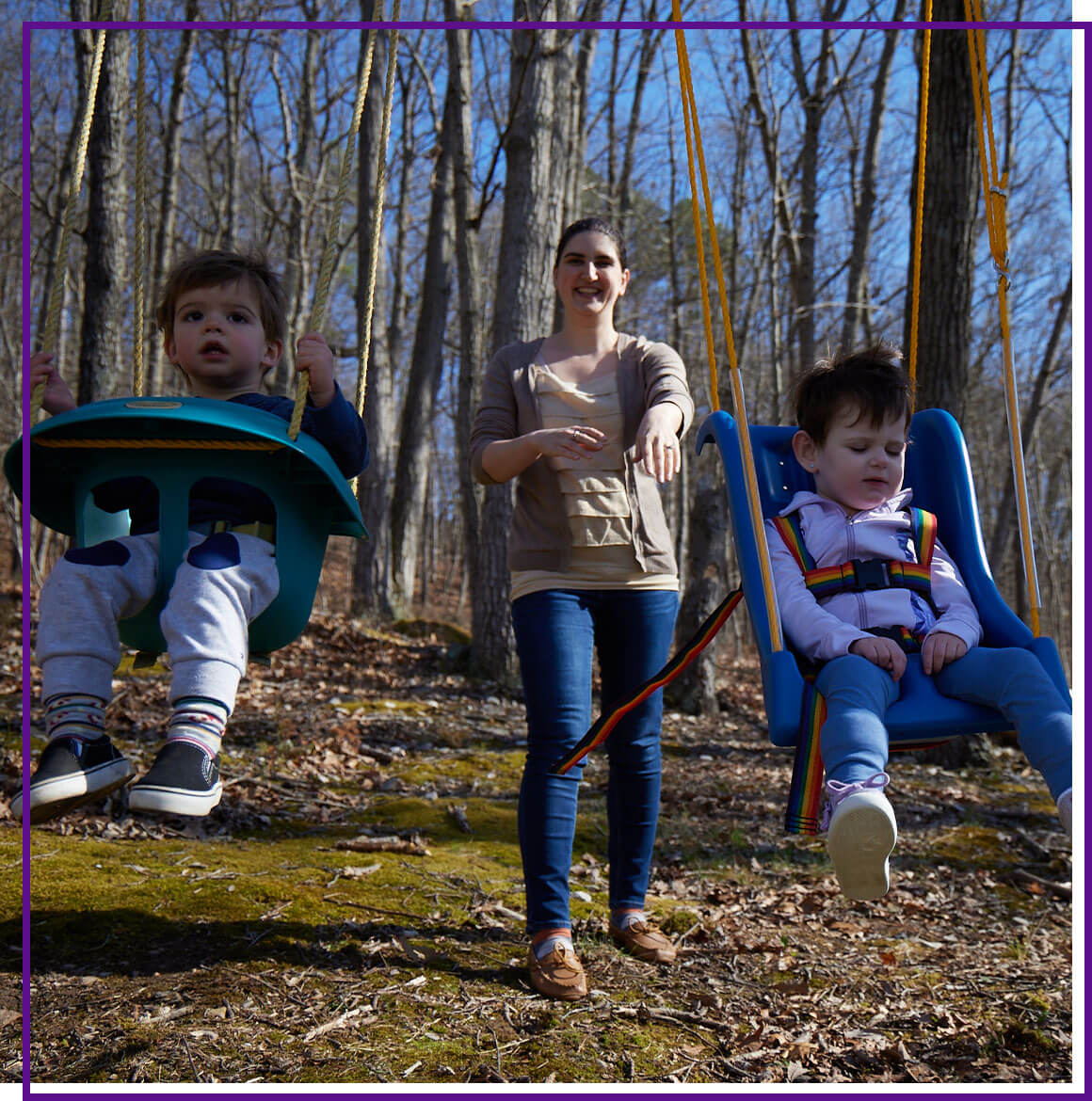 Mother outside with her two children, pushing them on the swings